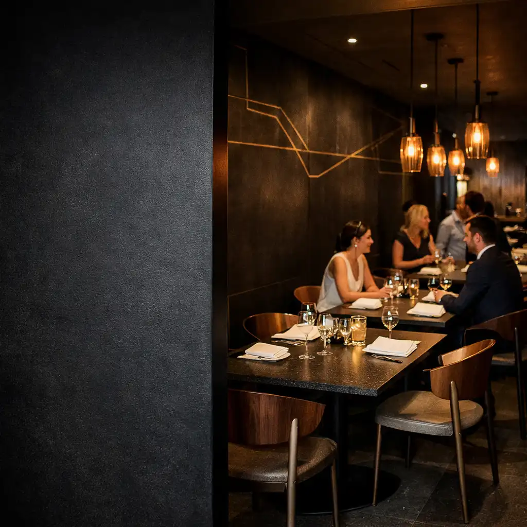Warmly lit contemporary dining room with dark stone, sculptural seating and carefully set tables at Gilded Card House